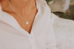 Delicate silver necklace with Lakshmi stamped into coin pendant on model.